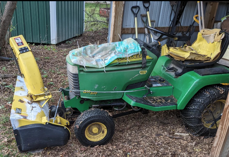 Picture of a John Deere 335GX with many cracked and broken plastic parts